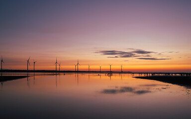 Obraz premium Sunset at Wind Farm Over Calm Waters