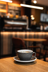 Cup of black coffee on the edge of a wooden table in a cafe coffee-shop with copy space