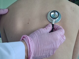Little girl has lungs examined by doctor with stethoscope