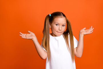 Photo portrait of pretty small girl shrug shoulders confused dont know wear trendy white outfit isolated on orange color background