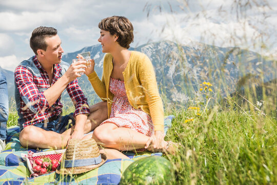 gl&uuml;ckliches Paar liegt in einer Wiese beim Picknick in den Bergen, &Ouml;sterreich
