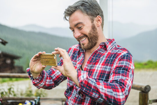 man taking a picture with oldschool cellphone in the mountains