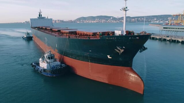 Huge cargo ship, towed by small towing boats