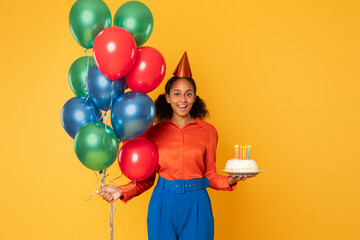 Fototapeta na wymiar African girl posing with colorful balloons and birthday cake, studio