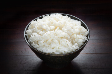 close up rice in black bowl on dark wooden background