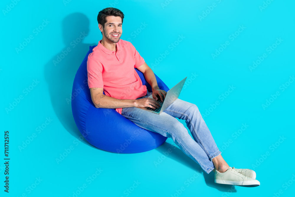 Poster full body size photo of young addicted workaholic man sitting pouf using netbook boost productivity 