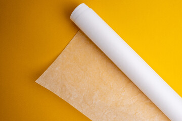 Plastic wrap, aluminum foil and a roll of parchment paper on a yellow background. Gadgets for the...