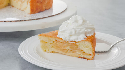 Chef serving an apple cake. Freshly baked fruit cake with whipped cream topping close-up on a plate
