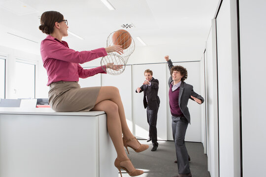 Mitarbeiter spielen Basketball mit Papierkorb im Büro, München, Deutschland
