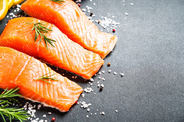 Salmon fillet, raw fresh fish with rosemary and spices at black background.