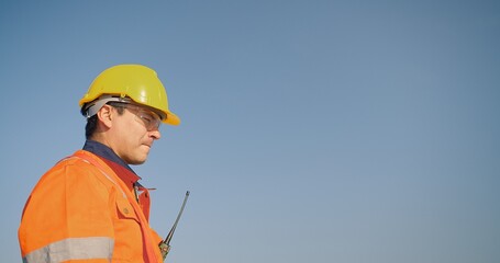 Portrait builder engineer man contractor worker foreman architect in hardhat on blue sky, construction manager in uniform and helmet work to maintenance of photovoltaic panel system at solar station