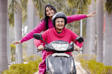 Indian Senior woman with Grand daughter Driving Scooter moped Enjoying Life ,Insurance Concept