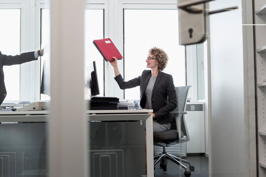 Female business manager passing on a folder in the office to colleague
