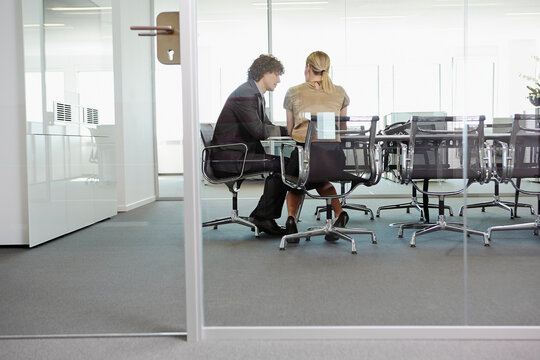 business people arguing  in a glass-walled conference room 