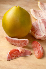Whole fresh red Pomelo and peeled pomelo slices close up