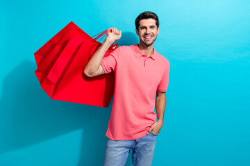 Photo of young handsome guy wearing pink t shirt and jeans holding red packages shopaholic isolated...