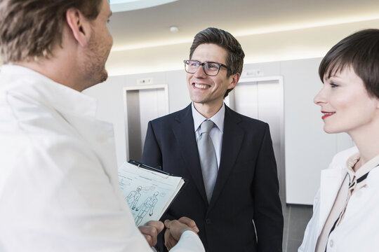Colleagues at a pharmaceutical company meeting with a client in the foyer. Munich, Bavaria, Germany