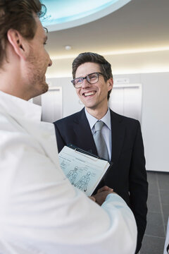 Colleagues at a pharmaceutical company meeting with a client in the foyer. Munich, Bavaria, Germany