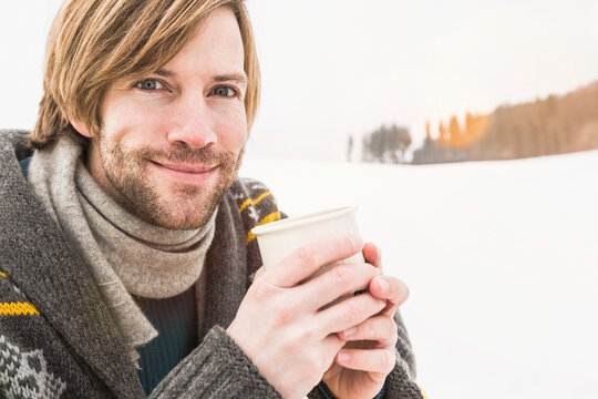 Man sitting on a sled and drinking tea in winter. Wolfratshausen, Bavaria, Germany 