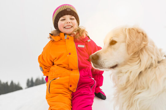 Young playing in the snow withe her dog. Wolfratshausen, Bavaria, Germany 