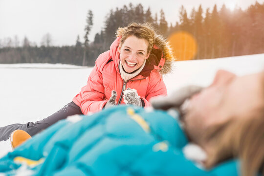Couple laughing in the camera after making snow angels in the snow in the winter. Wolfratshausen, Bavaria, Germany