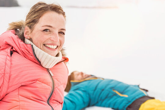 Couple laughing in the camera after making snow angels in the snow in the winter. Wolfratshausen, Bavaria, Germany