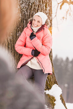 Woman looks into the camera with hat on her head in the snow in winter. Wolfratshausen, Bavaria, Germany