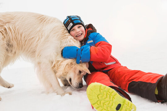 Young boy playing with his dog in a snowy landscape in winter. Wolfratshausen, Germany