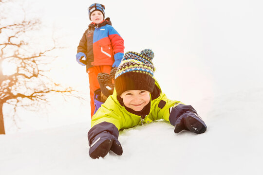 Two boys sledding and playing in a snowy landscape in winter. Wolfratshausen, Germany