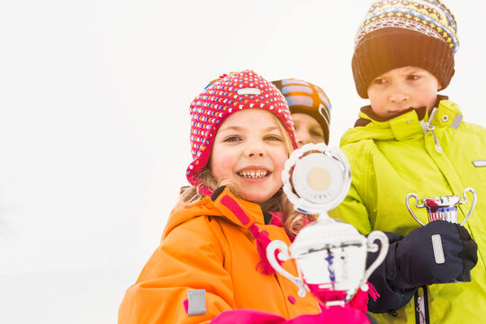 Three young kids holding up their trophies after winning a competition. Wolfratshausen, Germany