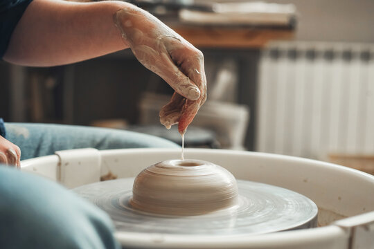 The hands of a Ceramist create pottery on a pottery wheel. Pottery, female hands of a potter creating a product from white clay
