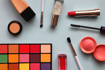 Various colorful make up products on bright blue background. Flat lay.