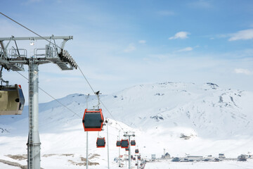 Cable car or ski lift cabins moving against the background of snow-covered mountains and blue sky in the mountain ski resort. Perspective. Winter, Vacation. Extreme sport.  Travel content