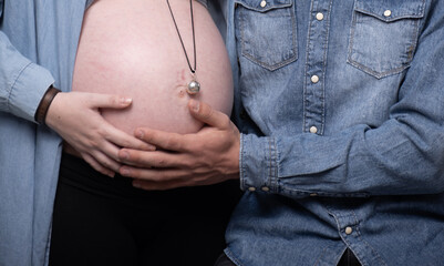 Ventre de femme enceinte avec un bola et les mains du futur papa