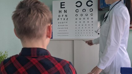 Ophthalmologist checking eyesight of teenage boy