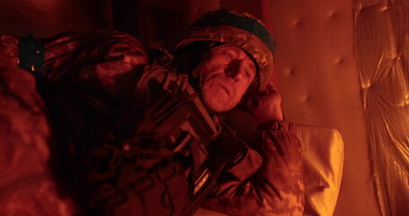 A soldier rests lying in a dugout in the glare of a burning trench candle. Ukrainian soldier in the...