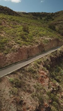 Race of cyclists in the Canary Islands, Cyclists between Mountains, Difficult Roads of Gran Canaria. Vertical Drone Recorded Cycling to 4K Quality.