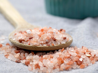 Pink salt piled onto a wooden spoon.