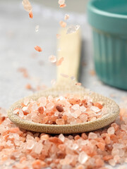 Concept of pink salt falling onto a spoon.