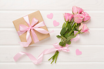 Pink roses with hearts and gift box on wooden background, top view. Valentines day concept