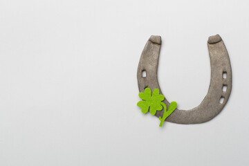 Metal horseshoe with clovers on color background, top view. St. Patricks day concept