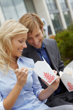 young business couple having take away lunch in front an office building