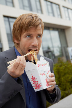 young business man having take away lunch in front an office building