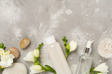 Flat lay with spa products and flowers on concrete background