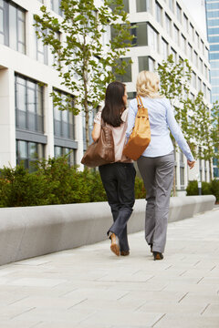 two young business women walking in front of an office building