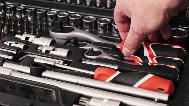 The mechanic takes out a socket wrench from his case.