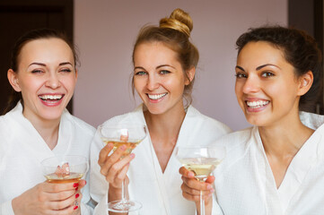 Young happy female friends drinking champagne in spa