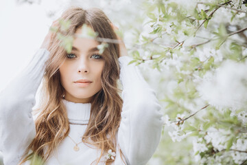 
portrait of a young girl with long hair and flowers on her head on the street. spring portrait. Awakening female beauty