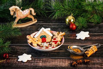 Gingerbread cookies, Christmas decorations, spices, candle, pine branches. Winter Christmas composition on a wooden background.