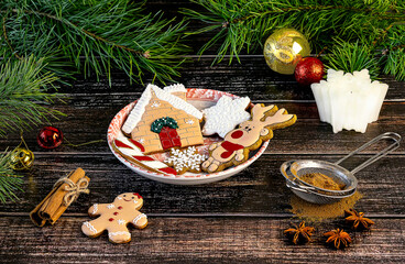 Gingerbread cookies, Christmas decorations, spices, candle, pine branches. Winter Christmas composition on a wooden background.